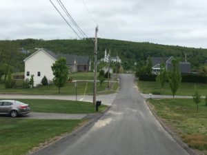 Looking down Stewart Street in Monson, Mass., toward downtown. Visible in the distance, the swath cut by the tornado in the Wilbraham Hills. Also visible is the steeple of 1st Church of Monson, which one couldn't see before the twister, according to Laura Yarbrough, whose home on this street was destroyed. (Mari Njiiri for NEPR)