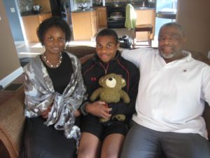 Yolanda, Caleb and Reverend Clyde Talley with the teddy bear recovered from their home in Springfield, Mass., which had been destroyed by the 2011 tornado.