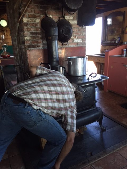Staff member Weston Lant prepares the cast iron wood stove.