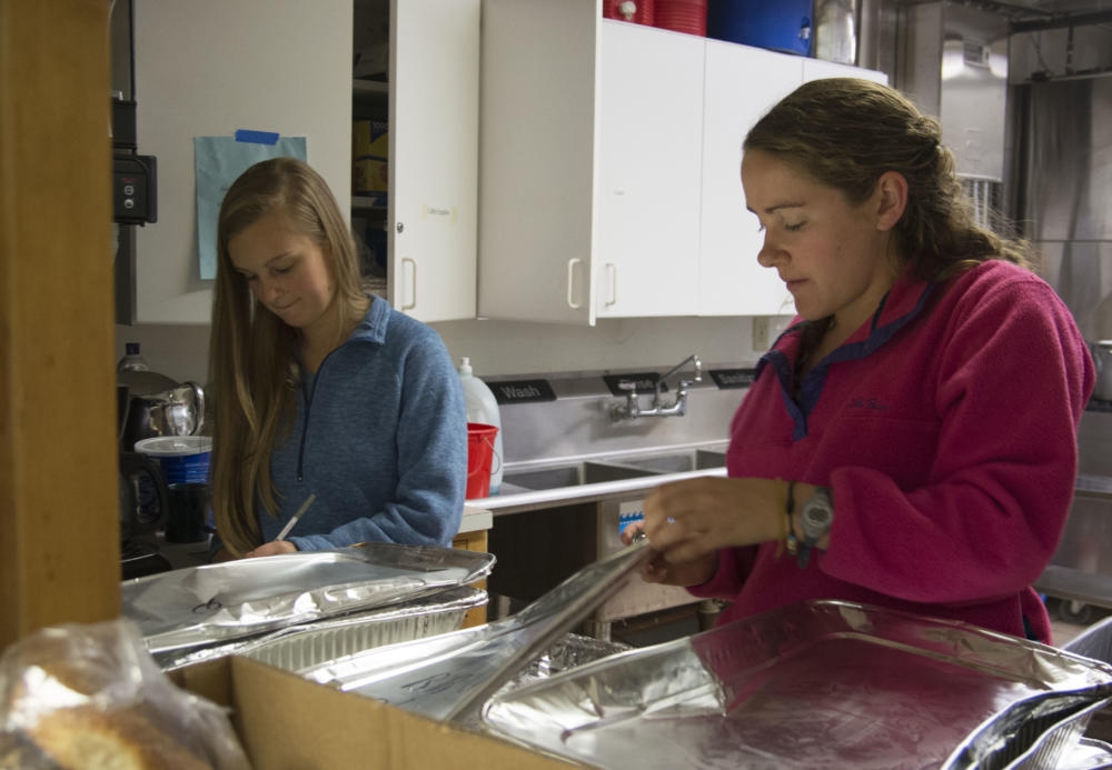 Kellan Morgan (left) and Shannon Flynn, check the temperatures of food being donated to Craig's Doors in Amherst. Student volunteers from UMass Amherst deliver food to the shelter five nights a week.
